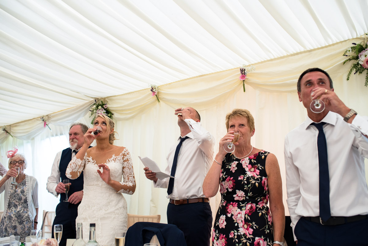 Toasting the wedding speeches with a drink at Paul and Lexy's Kent wedding