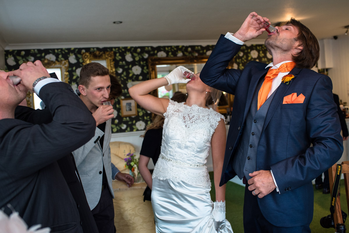 Photograph of wedding couple and their guests drinking shots at Great Chart reception venue.