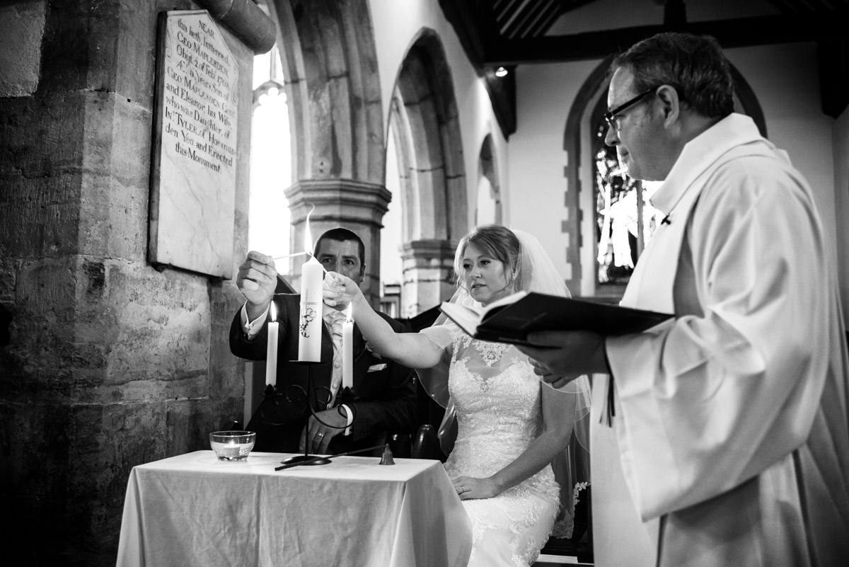 Kif & Becky are photographed lighting the candles during their wedding in Kent