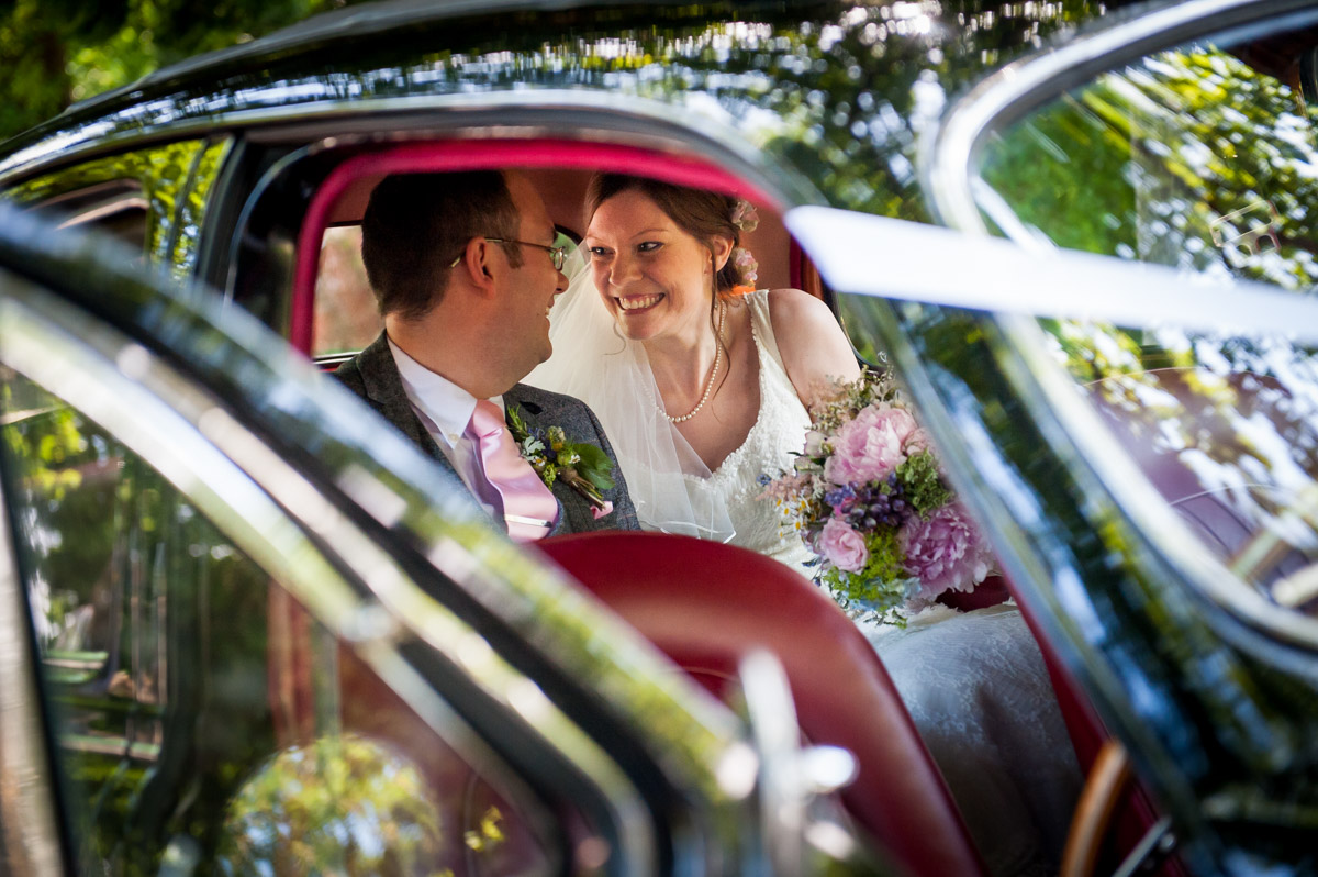 photograph of gaby and mark sitting in the back of their wedding car after their church ceremony