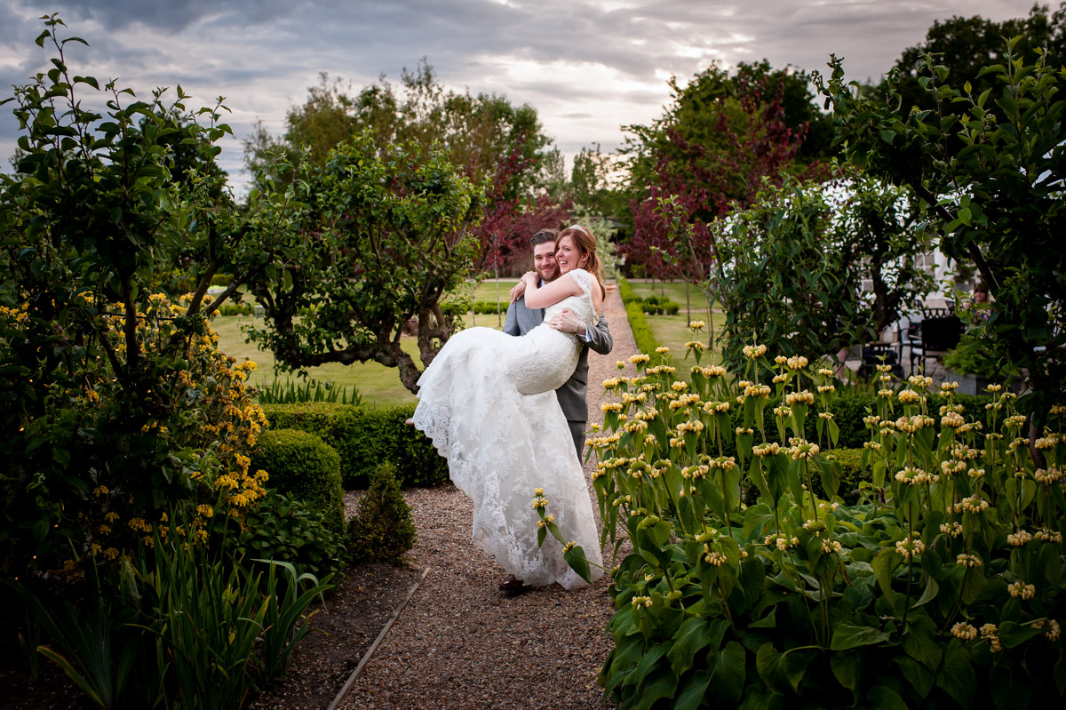 darren carries amy down the path at the secret garden in ashford on their wedding ay