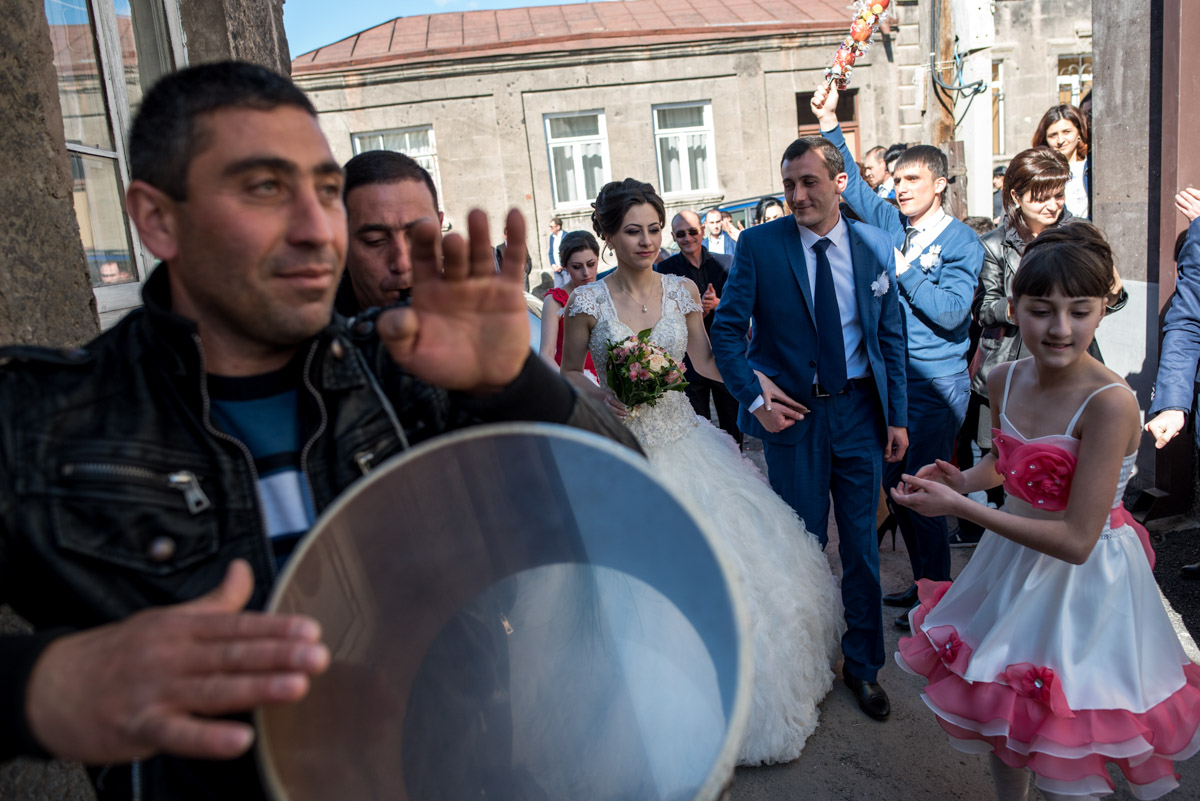 musician plays the drum to welcome bride and groom into their home after Armenian wedding ceremony