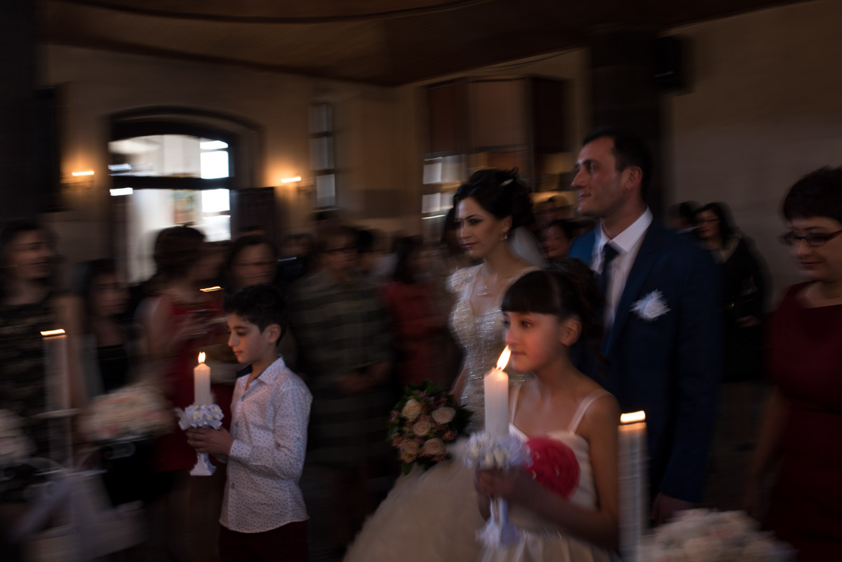 Armenian bride and groom walk up the church aisle with children holding candles