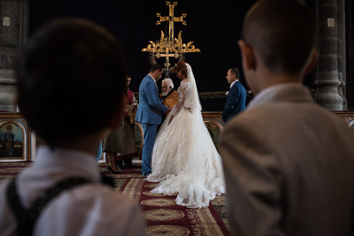 Photograph from the back of the church of armenian bride and groom taking their wedding vows