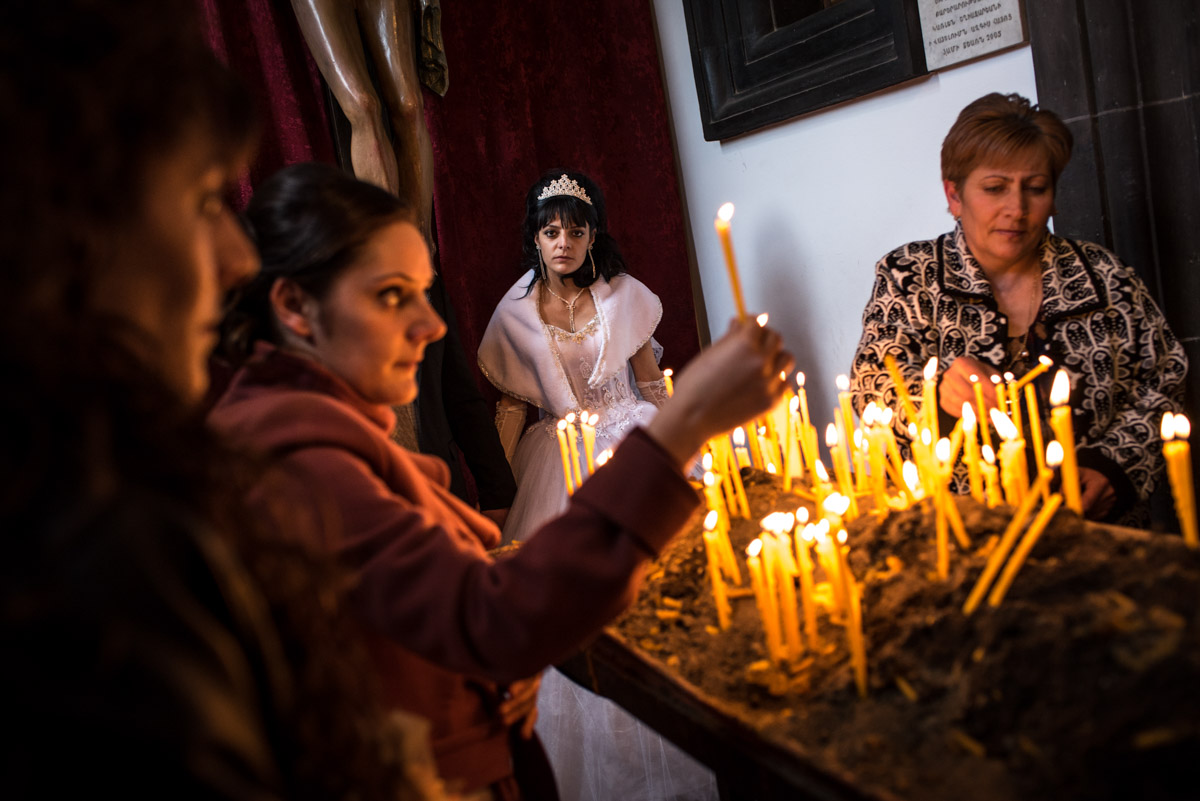 Photograph of sad looking armenian bride as church goers light candles