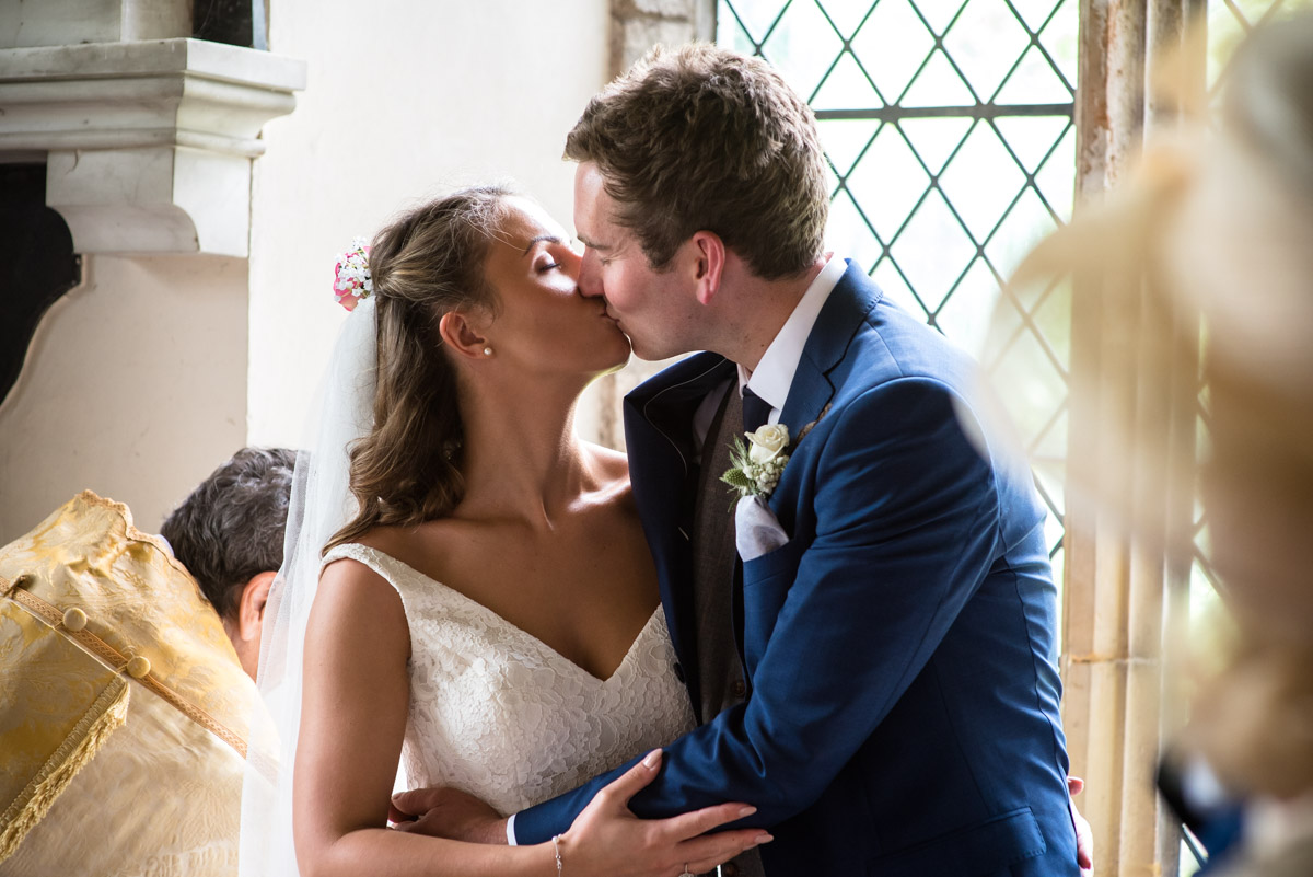 Ellie and james are photographed giving each other a kiss after signing the wedding register