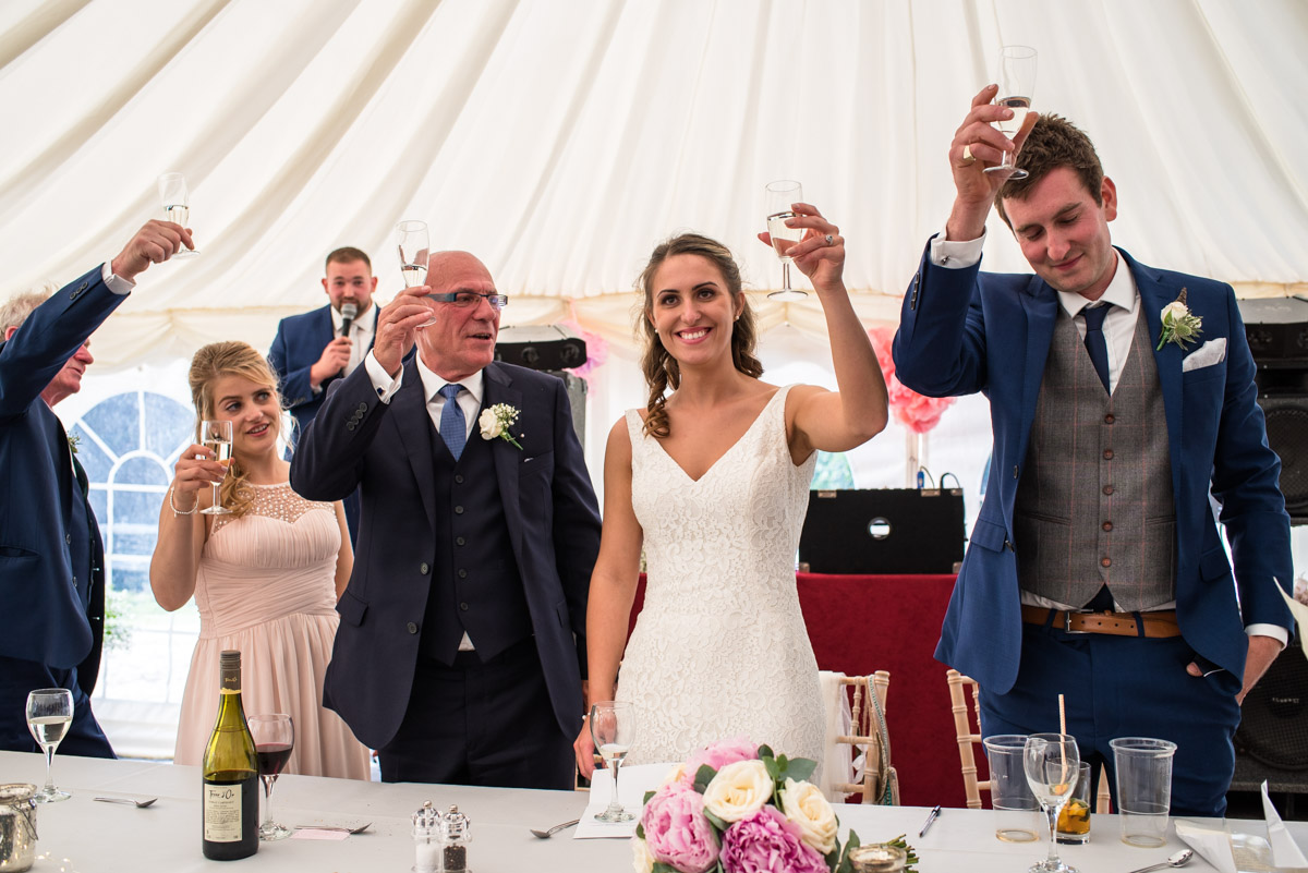 Ellie and James plus their wedding party are photographed toasting following best mans speech