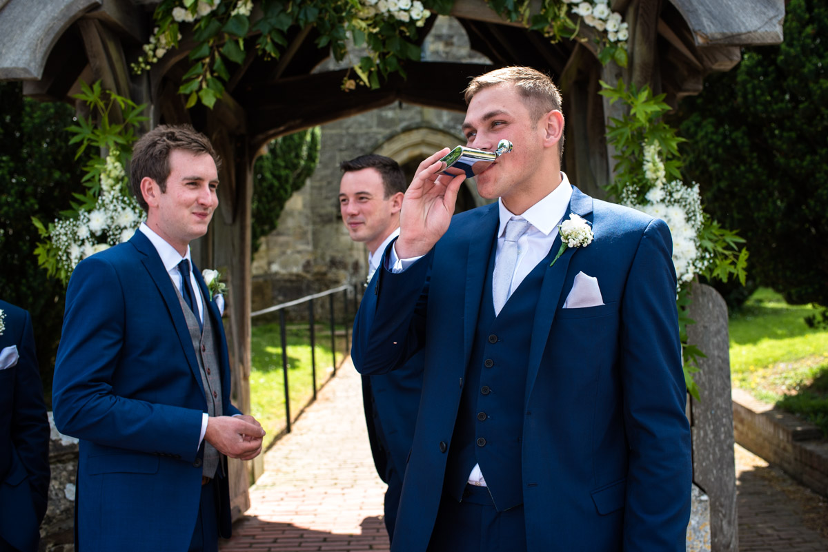 James and his groomsmen having a swig from the hip flask before his Kent wedding ceremony in St Georges church in Benenden, kent