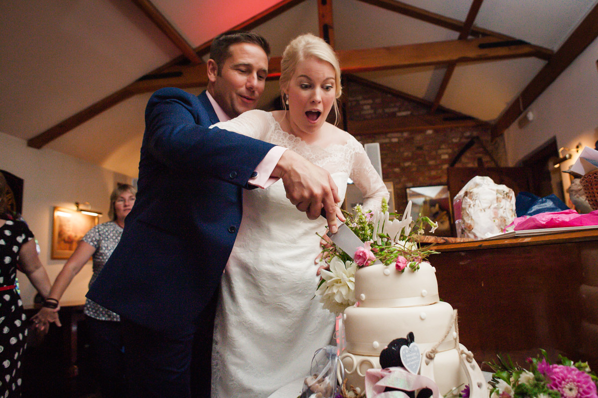Andrea and Matthew photographed cutting their wedding cake at Dering Arms reception in Kent village