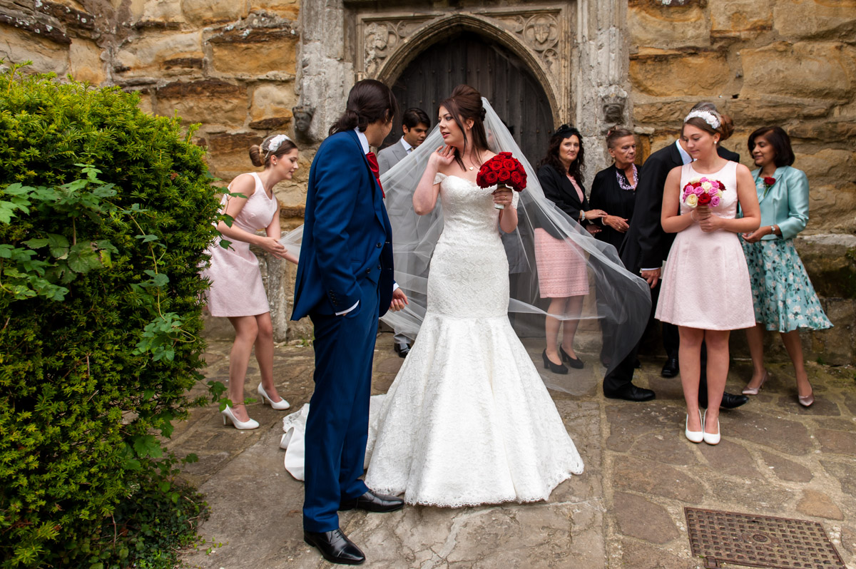 Bridesmaids adjust Mariannes veil outside church after wedding ceremony
