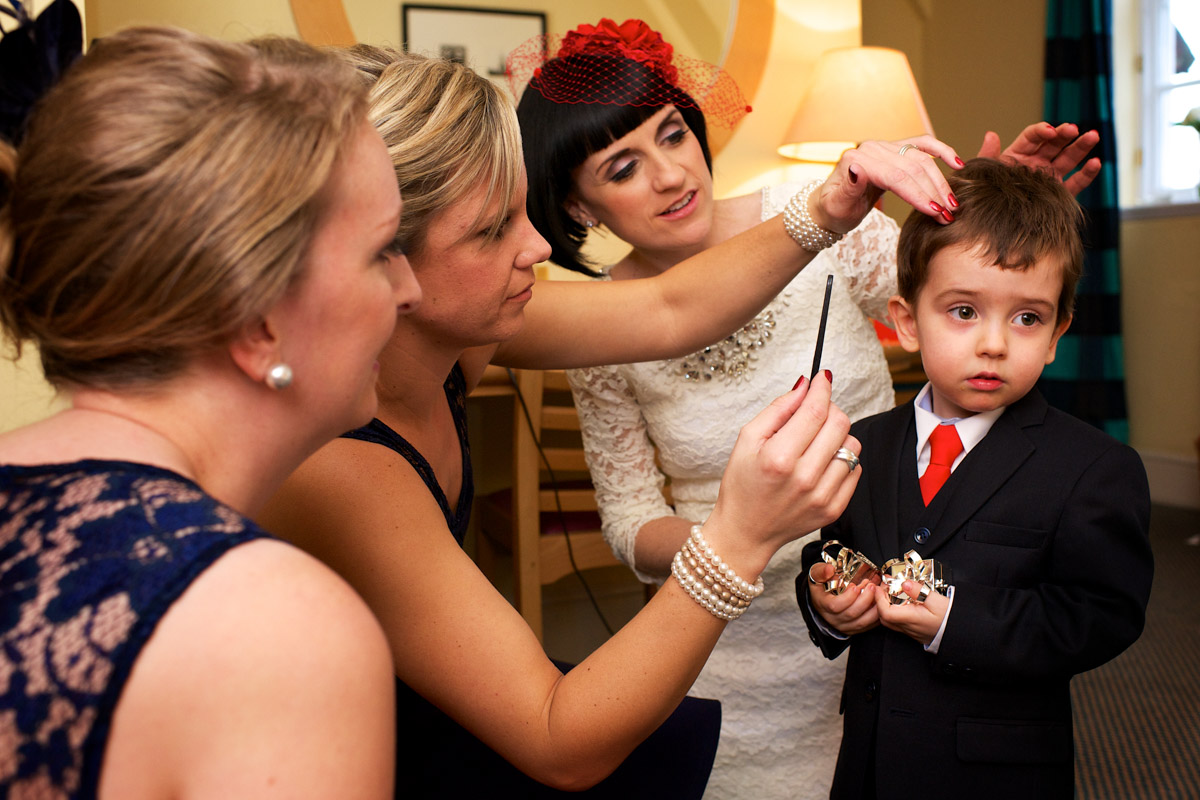Page boy is fussed over by three ladies before the civil partnership