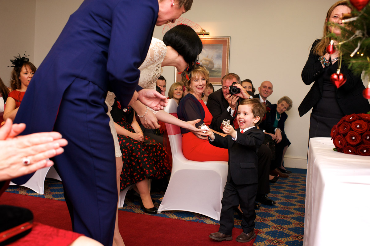 Page boy hands the rings over during anna and Robbies civil partnership ceremony