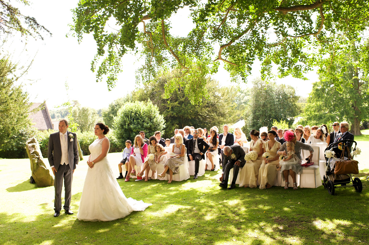 Tim and Andrea during their outdoor wedding at cobham hall looked on by their wedding guests