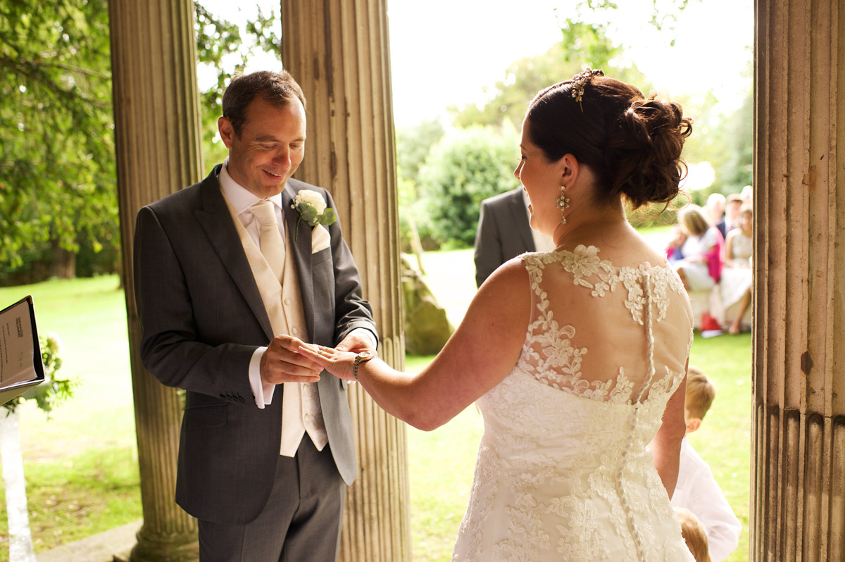 Tim puts the wedding ring on andreas finger during their cobham hall wedding ceremony