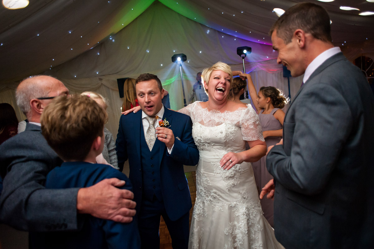 kelly and Stuart laugh with wedding guests photographed by Kent wedding photographer Helen Batt