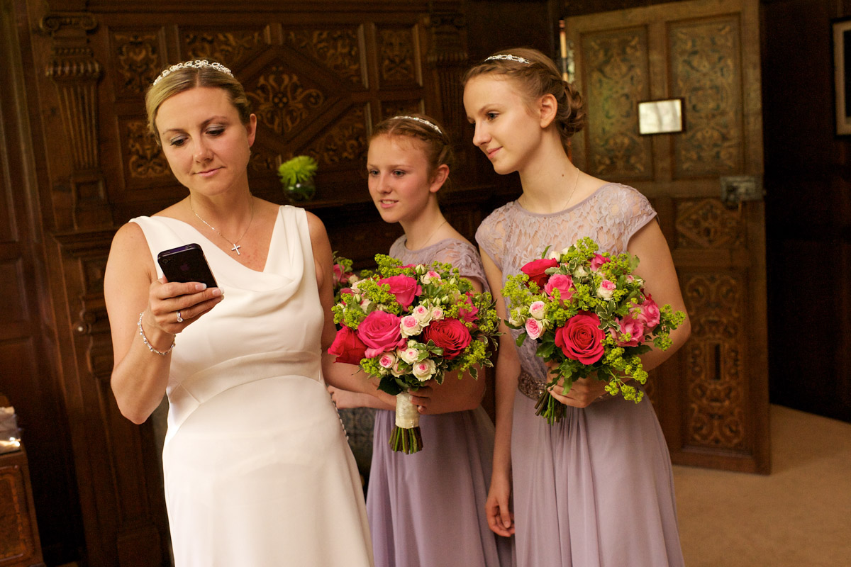 bride looks at her phone with her bridesmaids before her ceremony at never castle