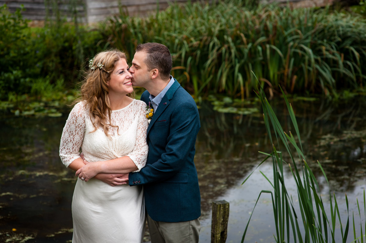 Photograph of Corinne and Doug by pond at Ratsbury barn after their wedding ceremony photographed by Helen Batt