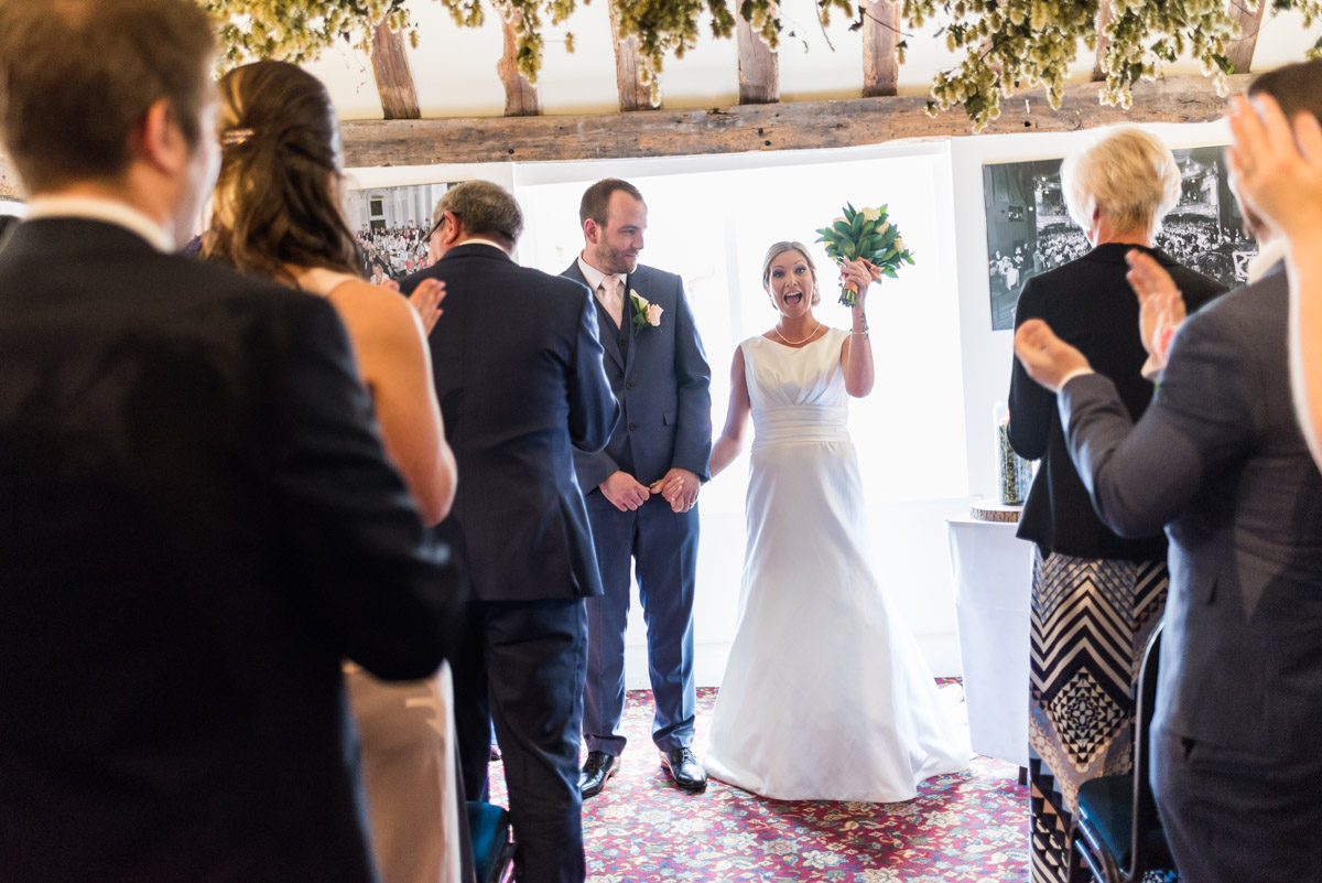 Louise is photographed lifting her wedding bouquet after ceremony