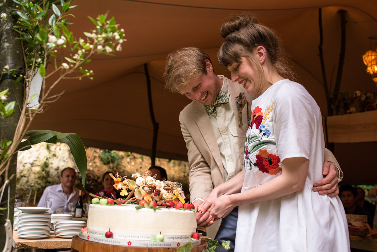 Seb and Brogan are photographed cutting their wedding cake at their celebration in kent