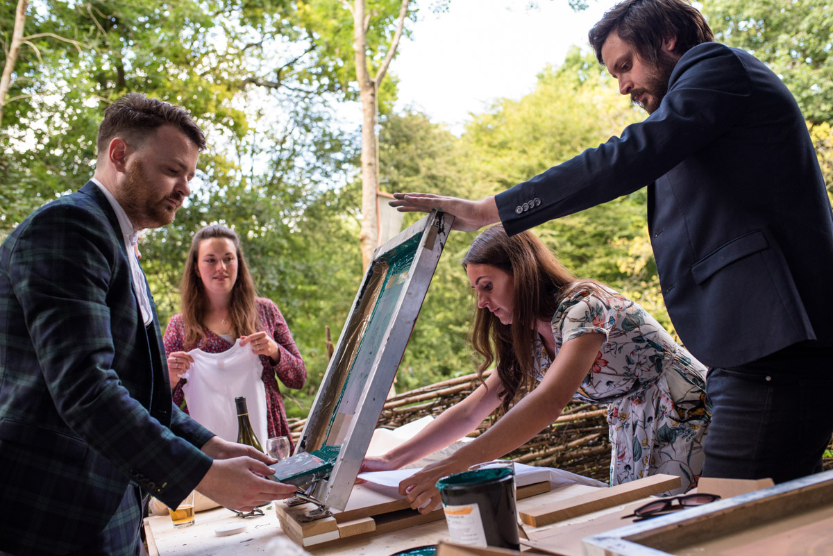 wedding guests are photographed trying their hands at screen printing