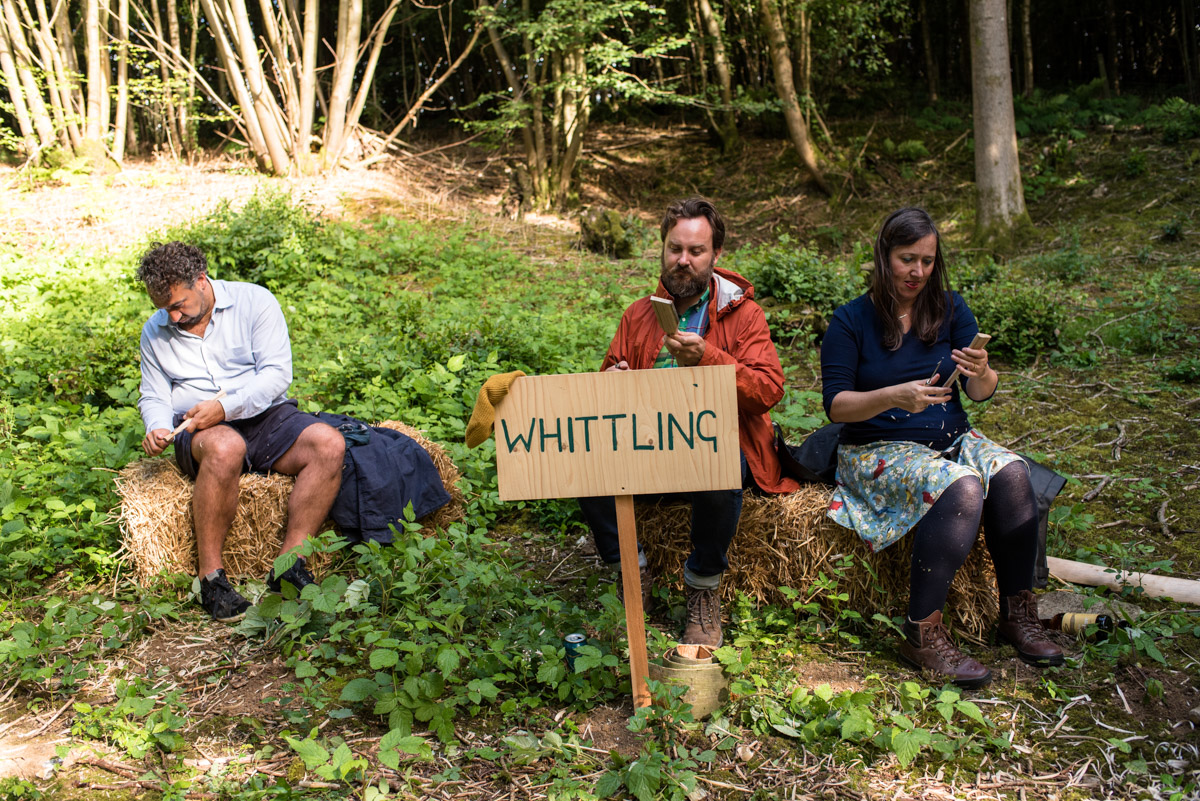 Photograph of wedding guests trying spoon whittling at sea and Brogans Kent woodland party