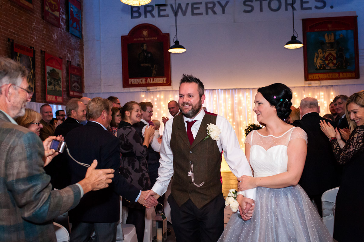 Laura and Daniel photographed walking up the aisle at Kent venue Shepherd Neame