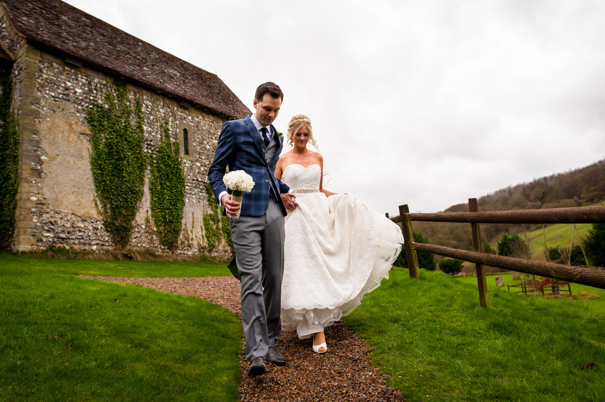 Photograph of Sara and Phil walking down the path outside their wedding venue in Kent