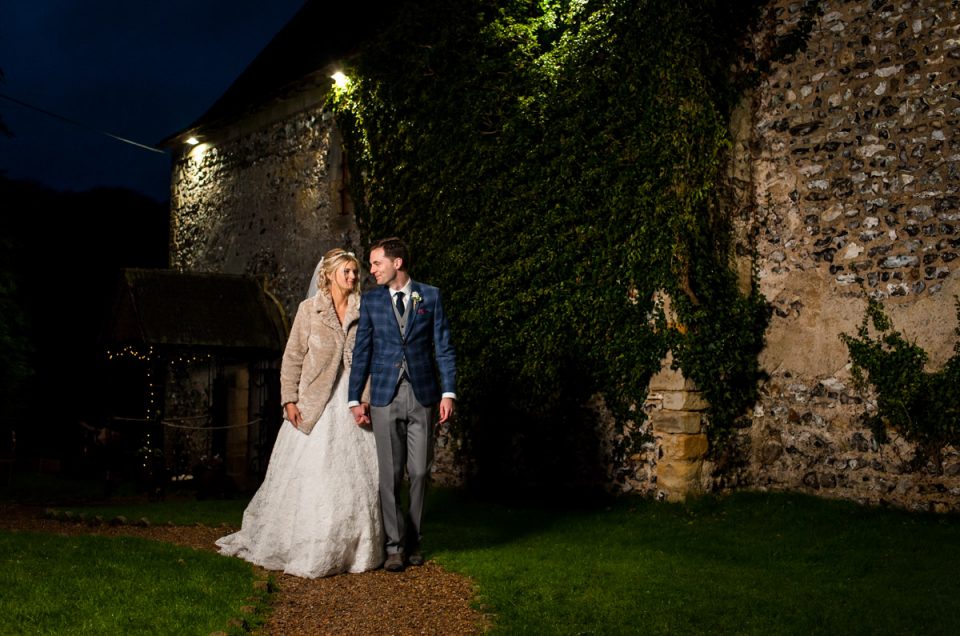 Phil and Sara are photographed walking hand in hand by their wedding venue in Kent