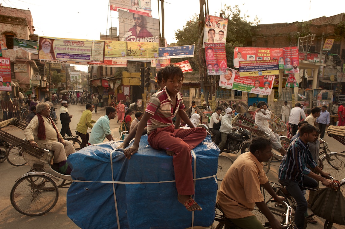 Boy sits on top of rickshaw in streets of varanasi