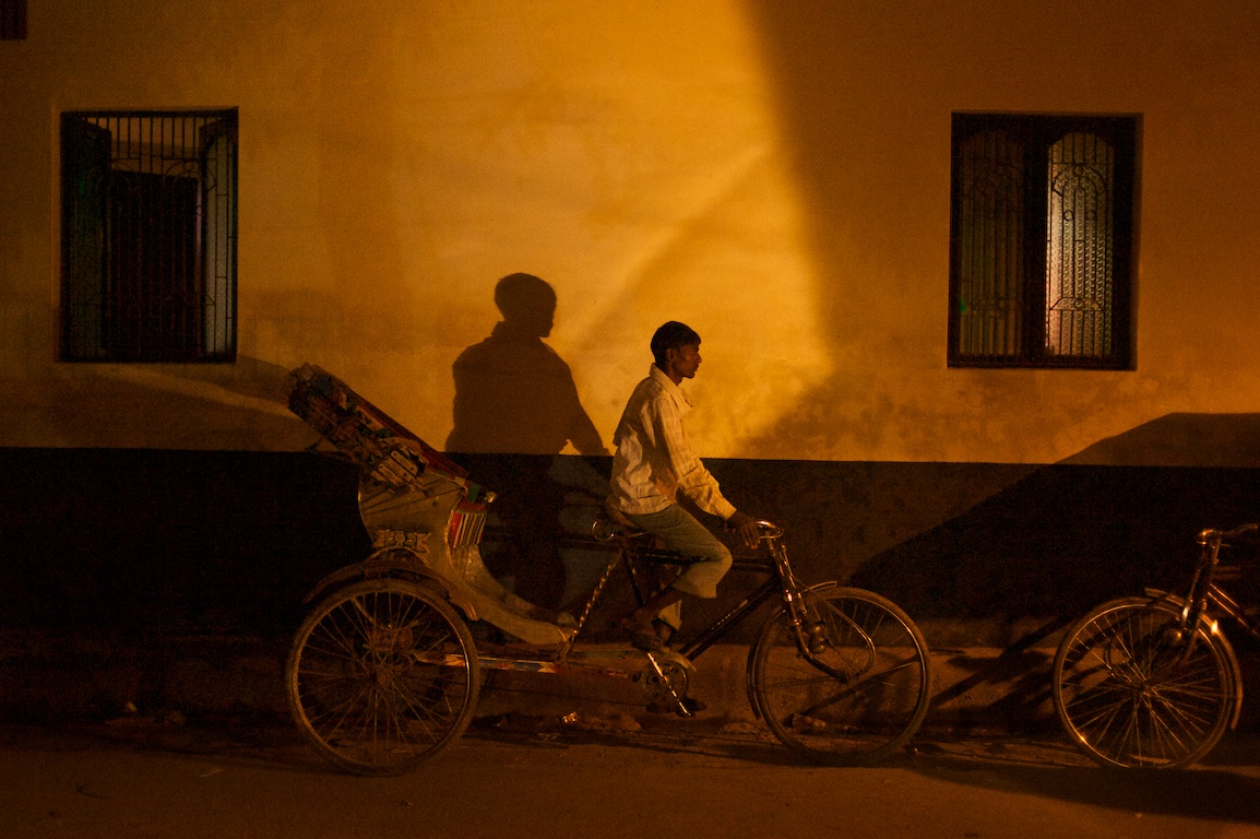 Photograph of man on rickshaw at night