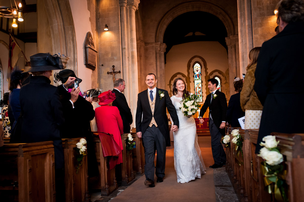 Photograph of Emma and Ollie walking back down then aisle after their wedding ceremony