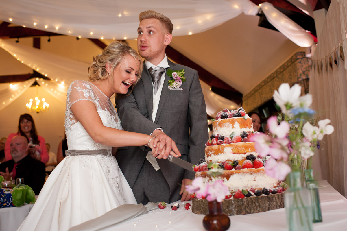Aimee and Billy cut their cake at wedding at Rare Breeds Centre