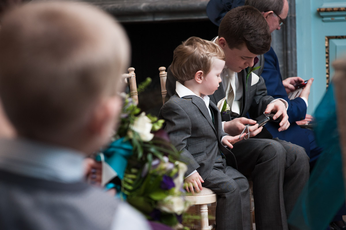 Two pageboys play with their camera after the wedding ceremony