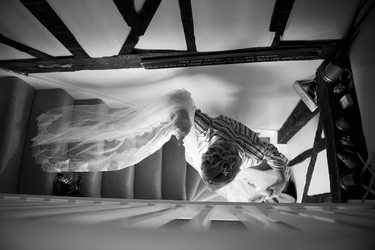 Photograph of Katie carrying her wedding dress down the stairs
