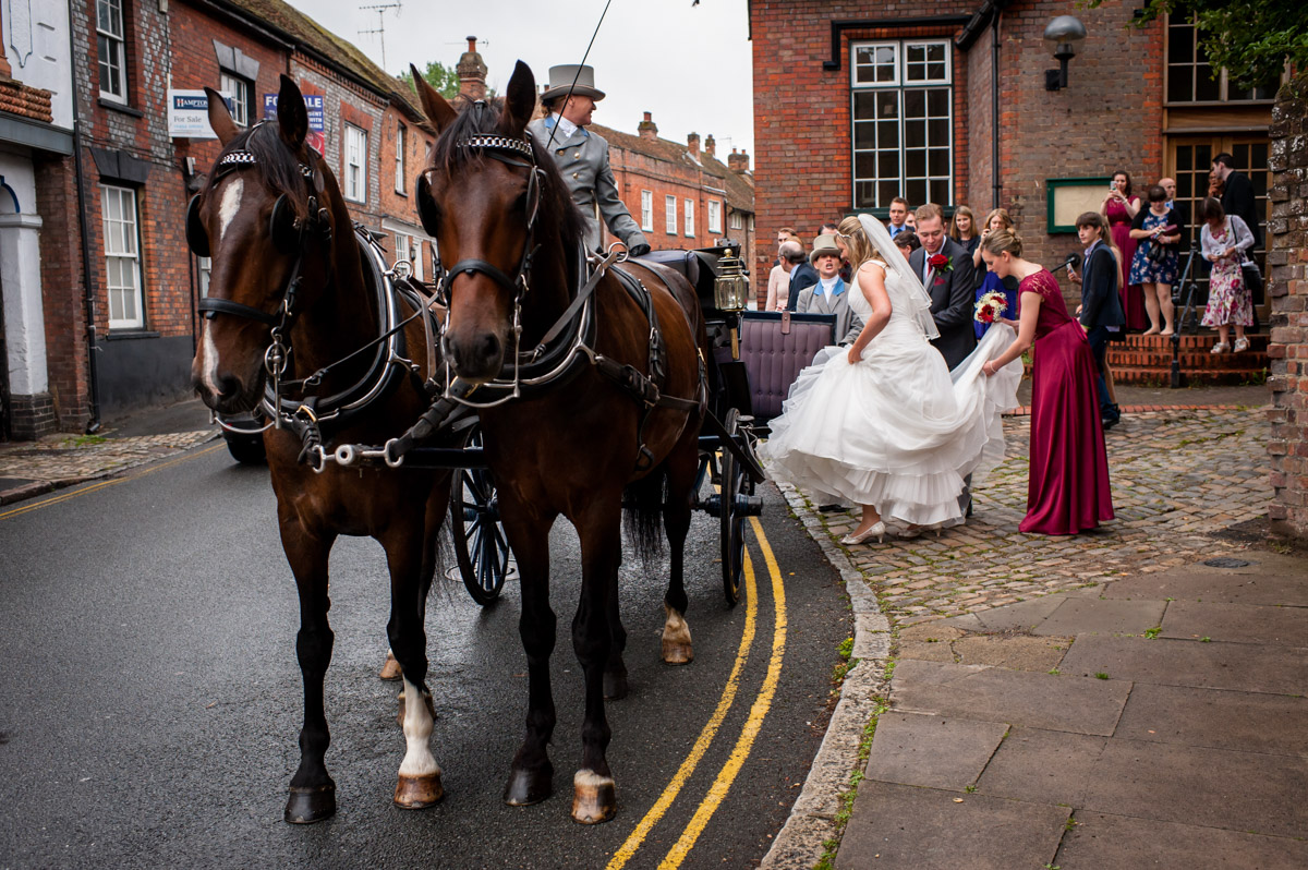Bride and groom alight horse drawn carriage for wedding