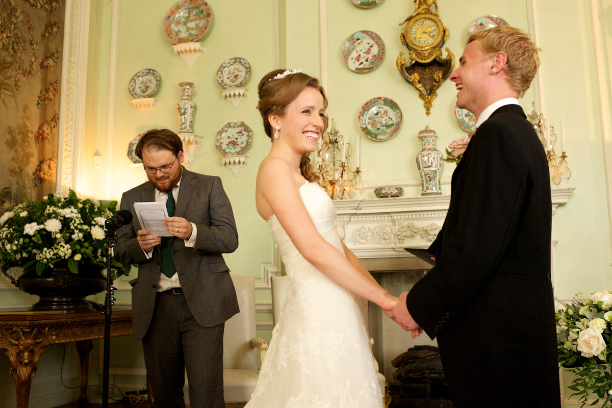 timea and edmund laugh listening to reading during their wedding ceremony at leeds castle in kent