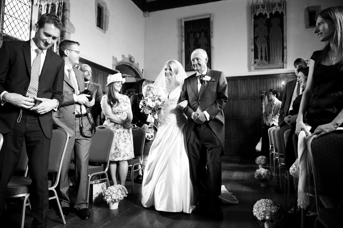 Photograph of Sarah being escorted by her father down the aisle at lympne castle in Kent on her wedding day