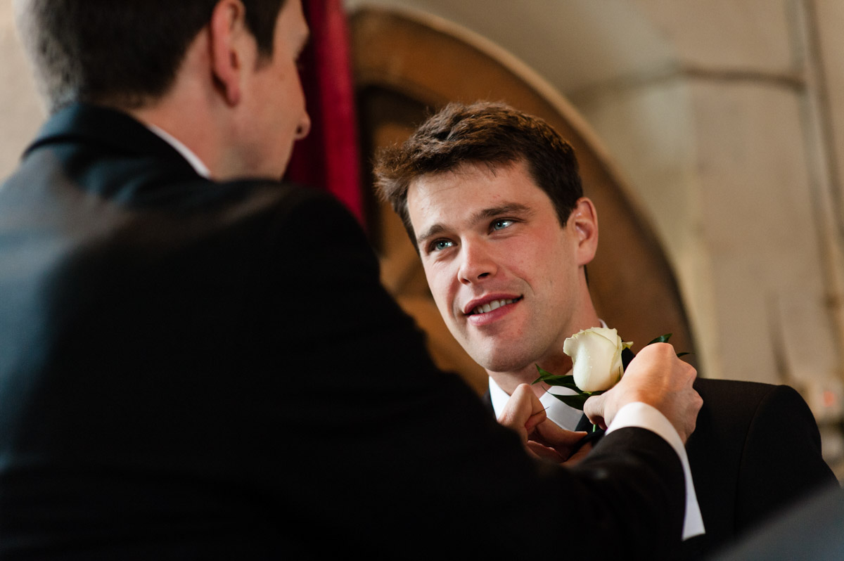 groom Nick has his button hole fixed by groomsman at pet ham church in Kent before his wedding