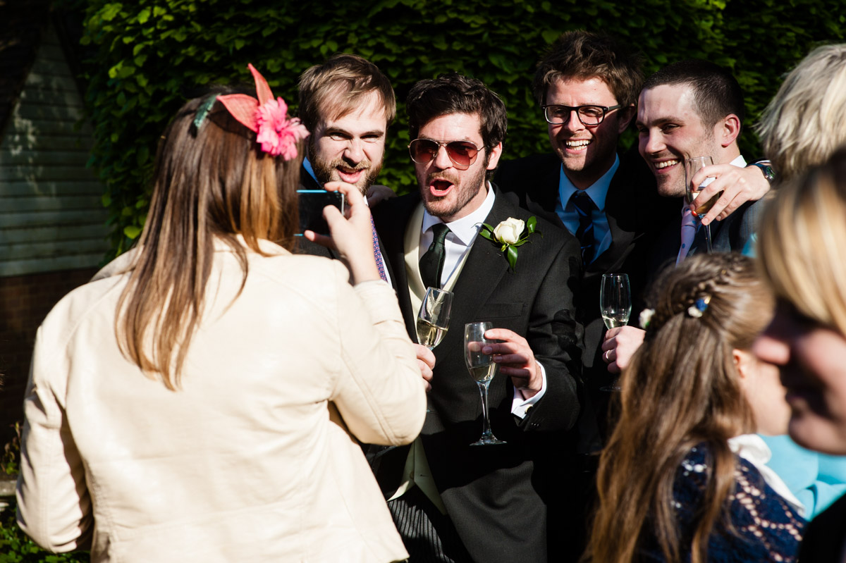 wedding guests are photographed photographing each other at garden wedding reception
