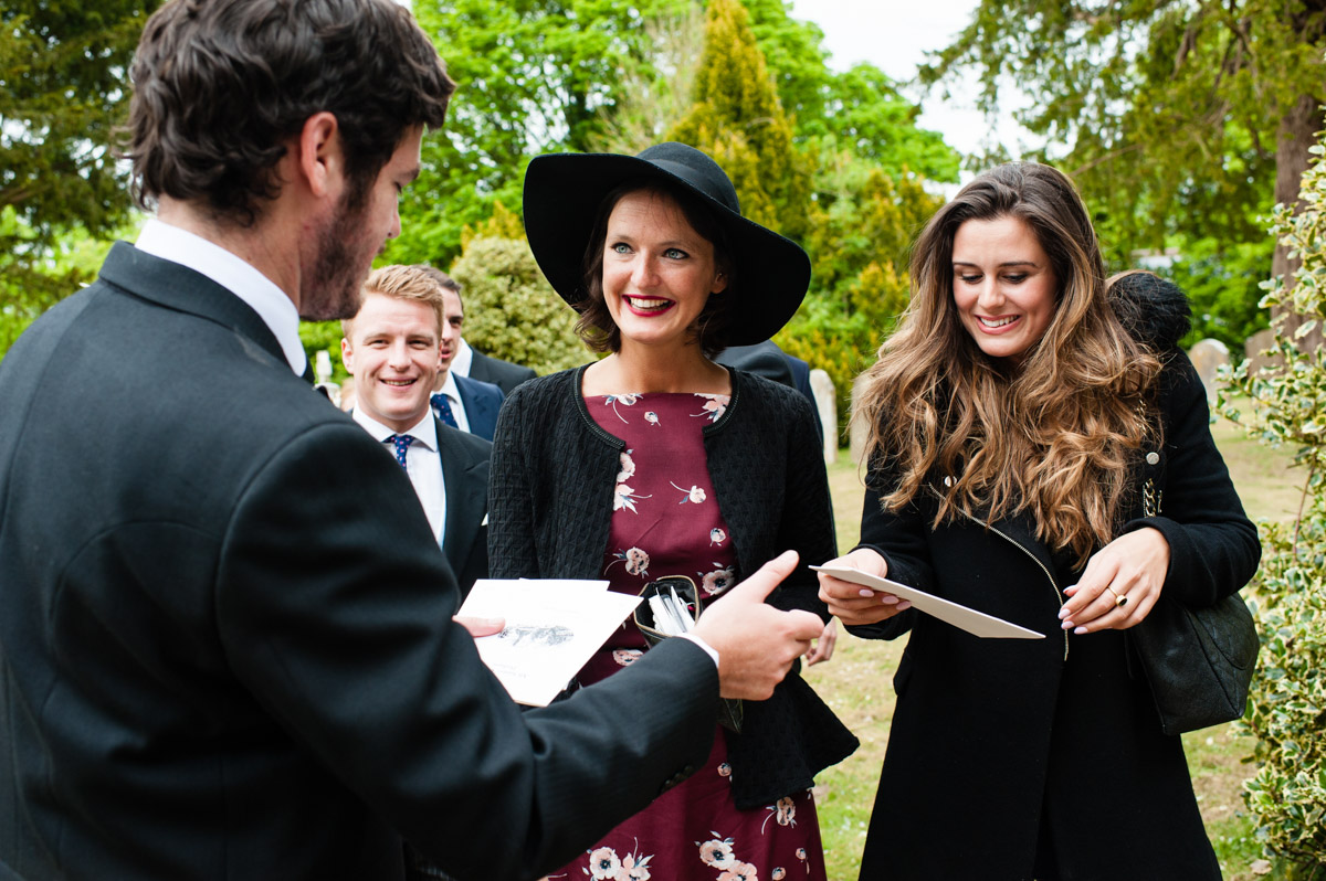 wedding guests receive order of service before Nick and Olivias wedding in Kent church