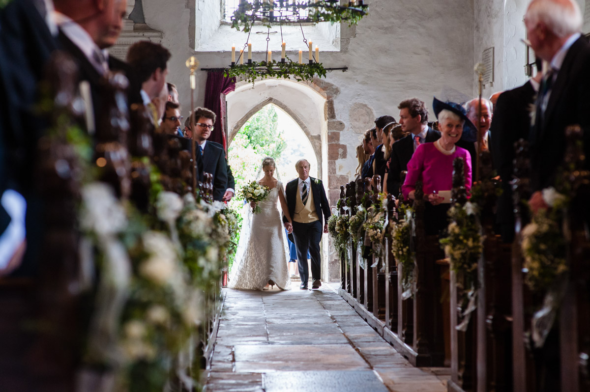 Olivia the bride is walked down Petham Church aisle by her father on her wedding day