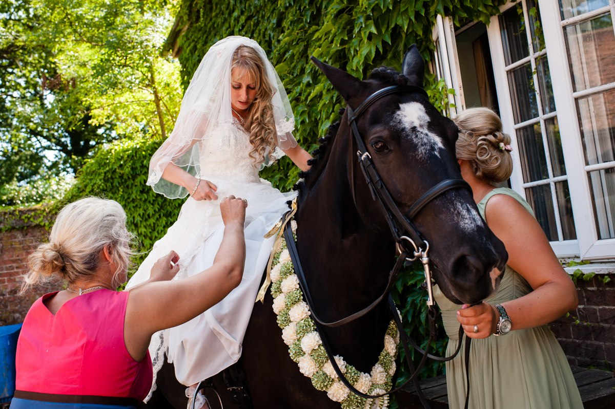 bride photographed on her wedding day at st augustines priory jut after getting on her horse