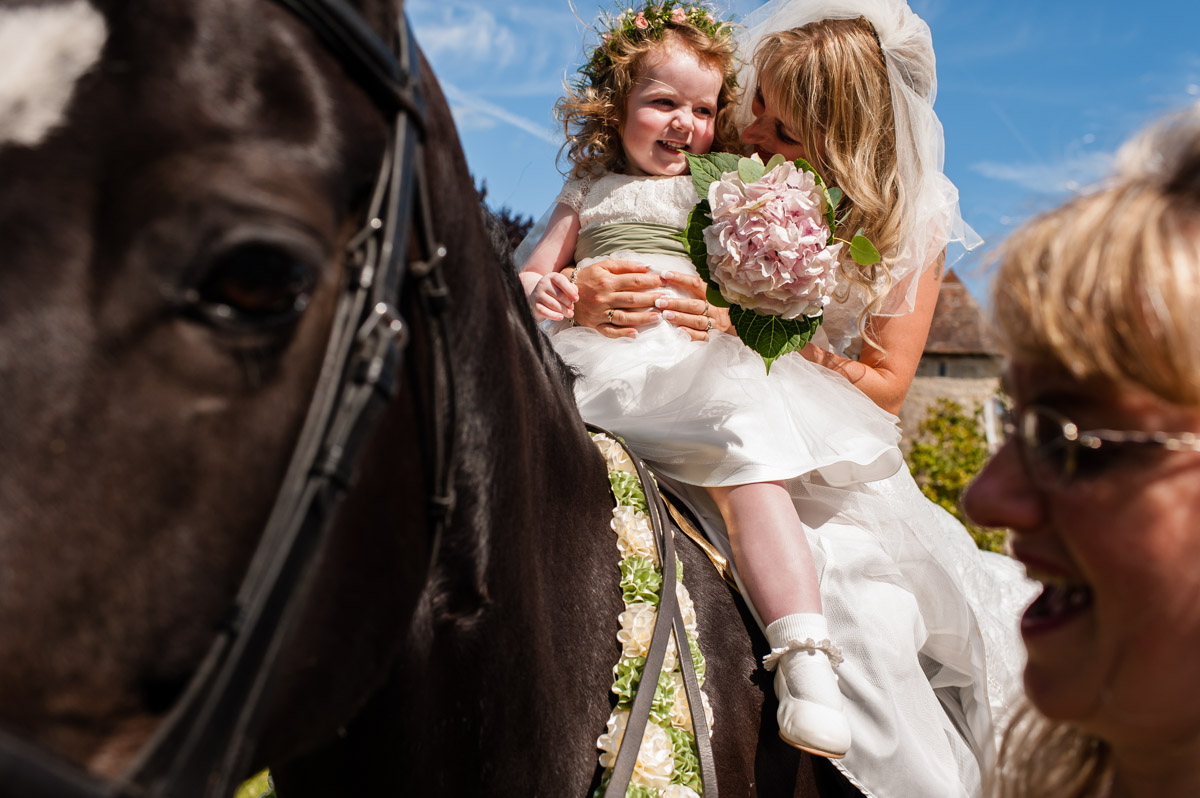 bride and flower girl photographed on horse outside st augustines priory after her wedding ceremony