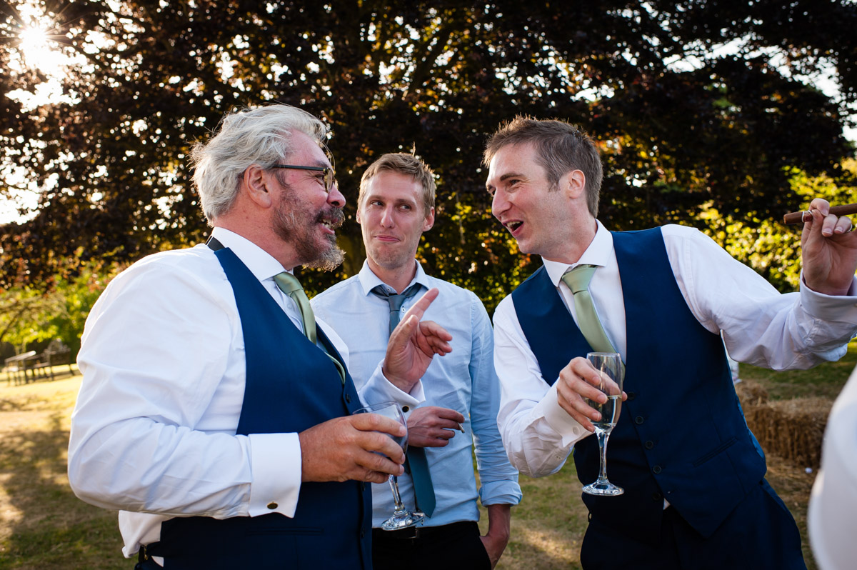 groomsmen talking at wedding reception at st augustines priory in kent
