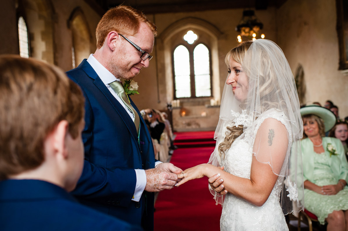 Mark is photographed placing wedding ring on salinas finger during their wedding ceremony in st augustines priory