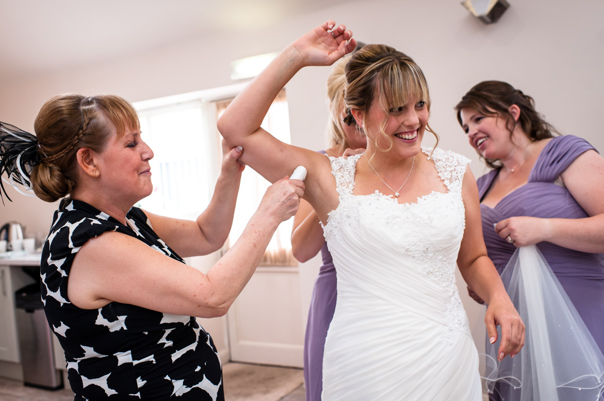 Brides mum and bridesmaids help bride get ready for her wedding Winters Barn
