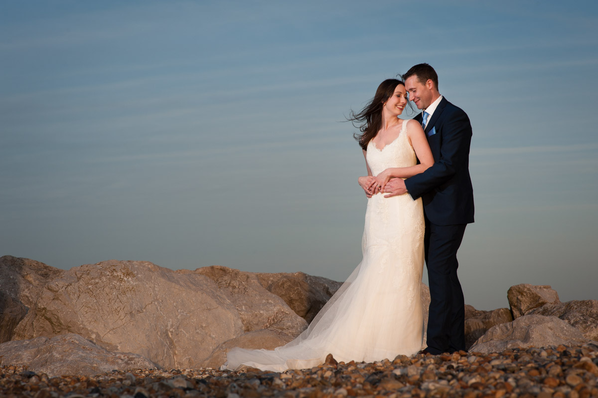 Off camera flash lights couple during wedding portrait session on the beach at Hythe