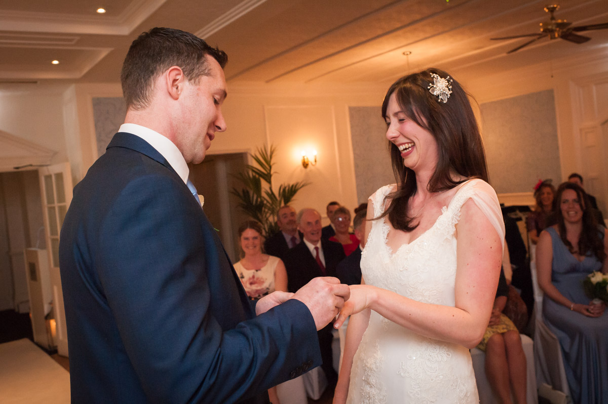 Groom places ring on brides finger during wedding ceremony at Hythe Imperial