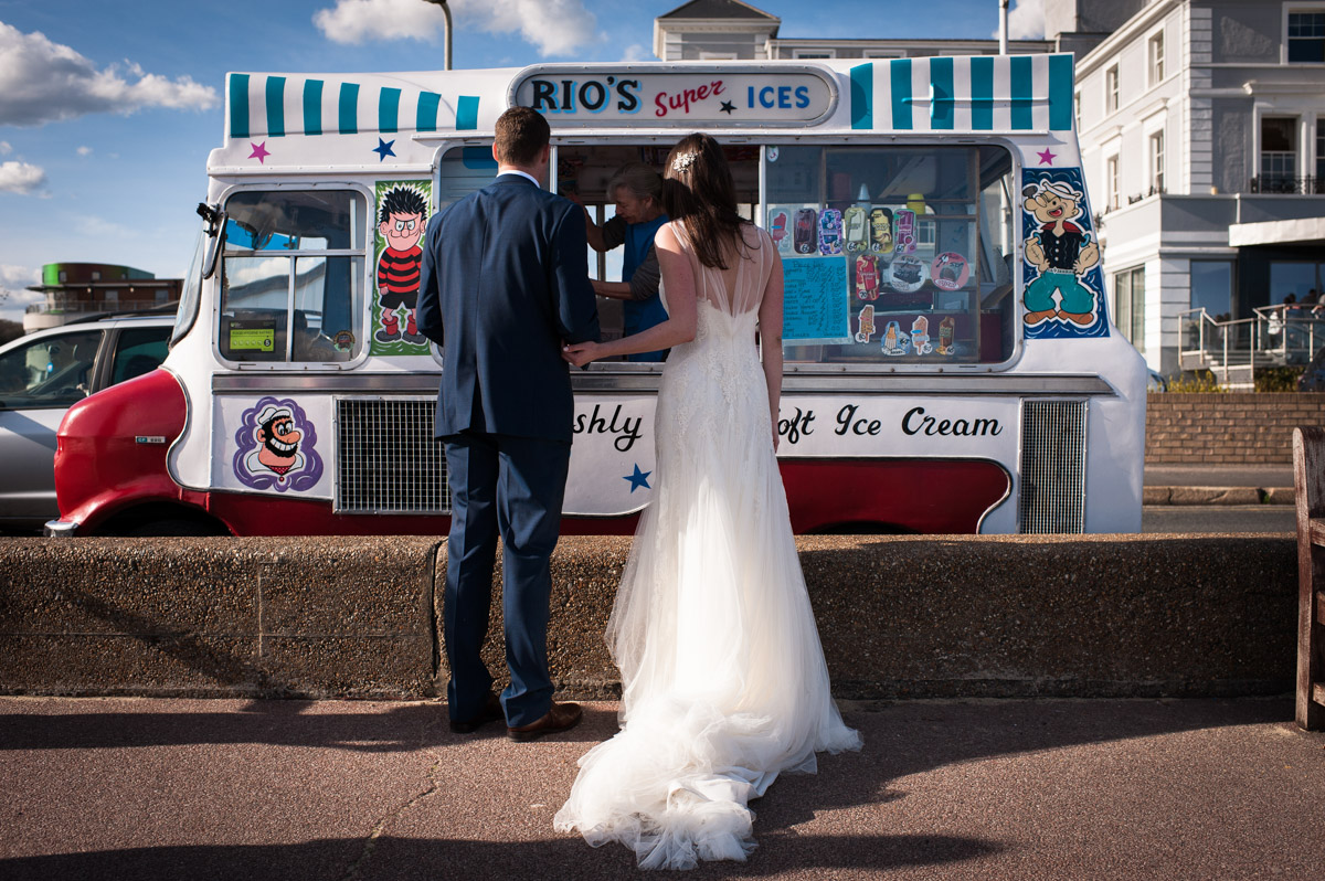 Julie and Chris are photographed queuing for an ice-cream after their wedding at The Hythe Imperial Hotel on Kent coast