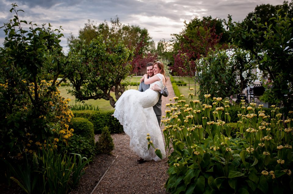 Darren carries amy down footpath at the secret garden in Kent after their wedding